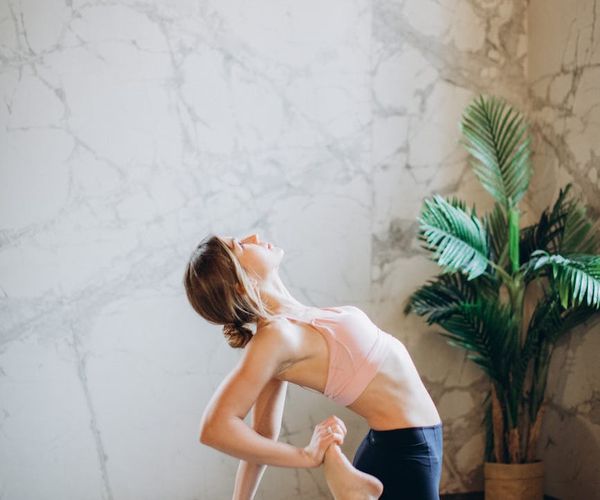 A person maintaining a difficult balance pose in a bright studio.